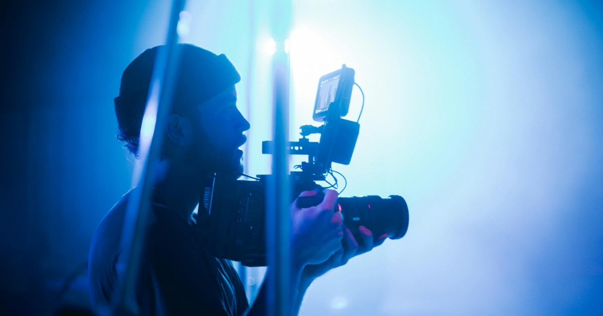 A professional videographer filming a creative project outdoors with a high-quality camera and tripod setup.